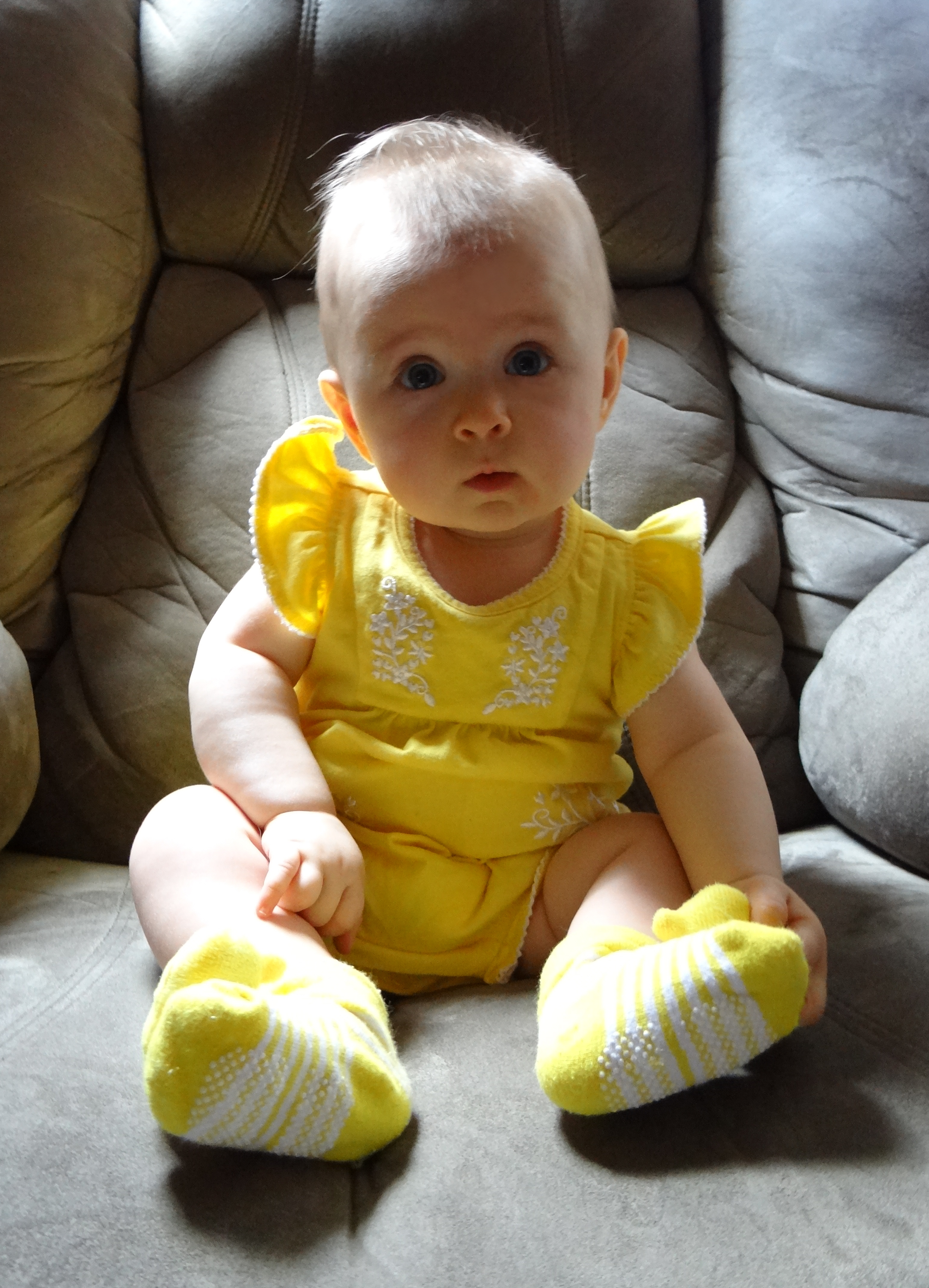 Infant wearing a yellow outfit sitting unassisted