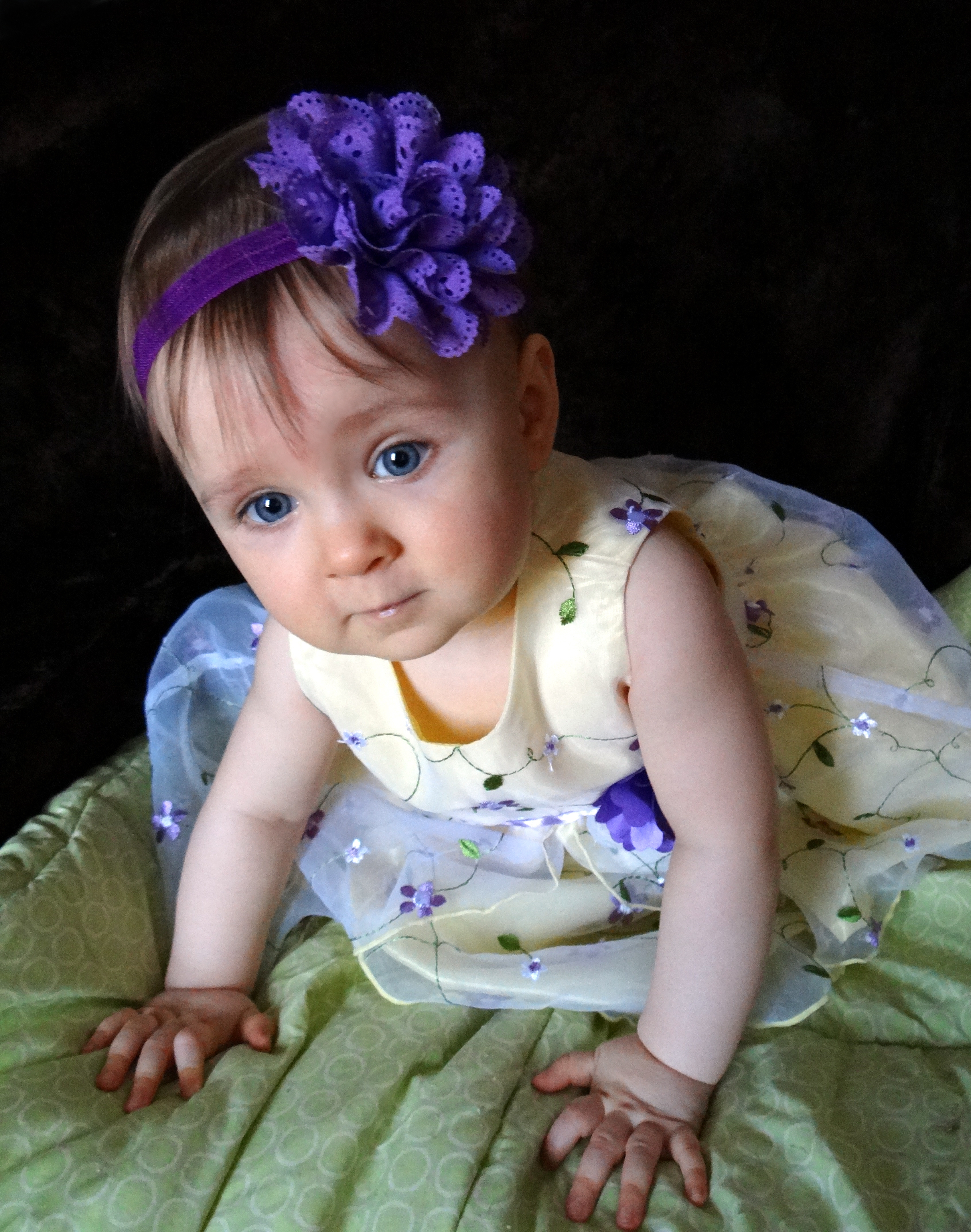 Baby dressed up in yellow dress with purple flowers