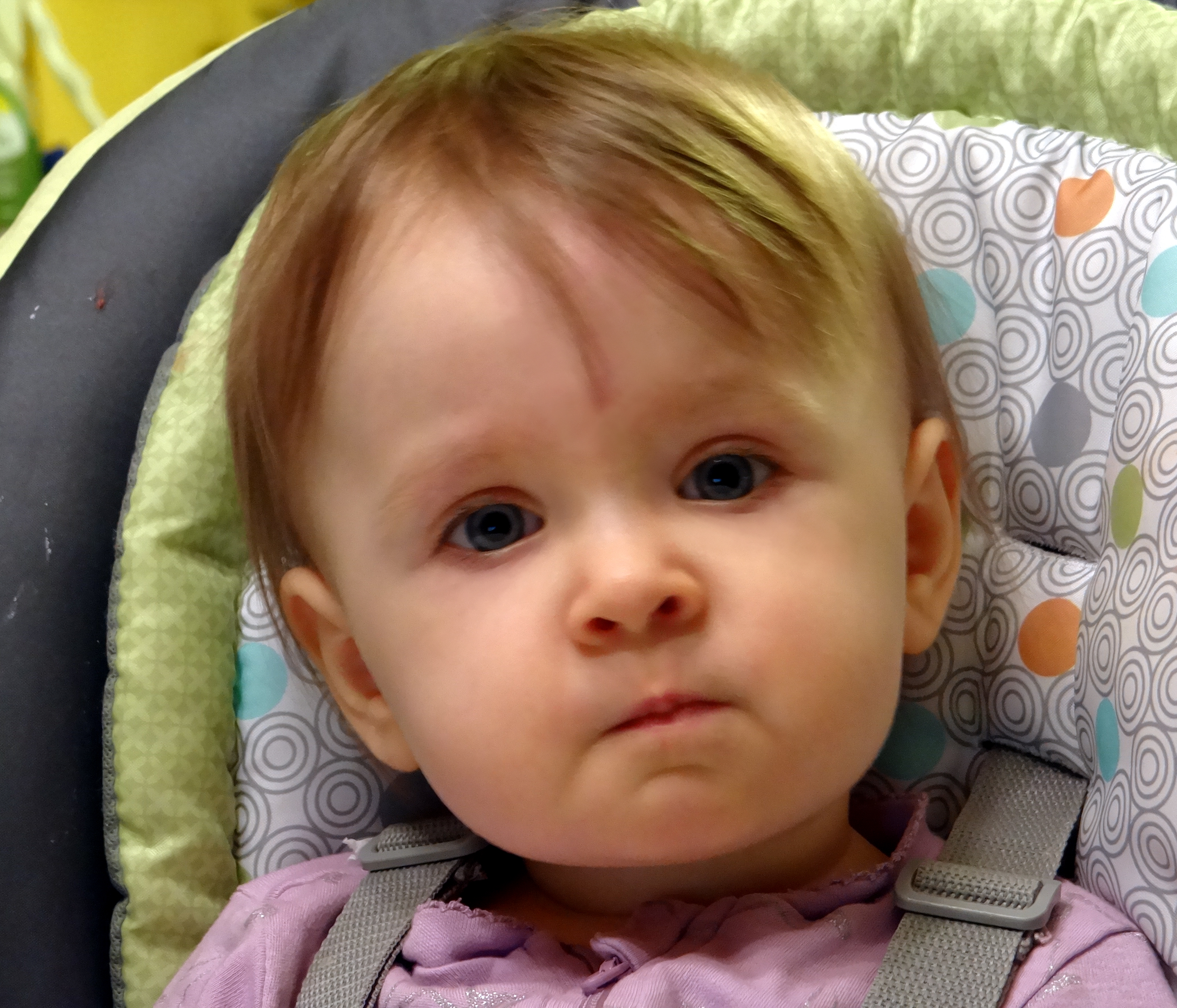 Baby in a high chair with a quizzical expression